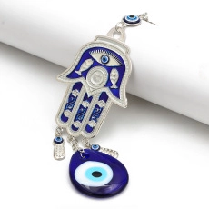 Close-up of silver Hamsa charm with blue Evil Eye and fish pattern on white scroll