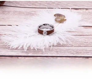 Detail of stainless steel ring with wood grain inlay and zircon on wooden background