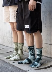 Détail de chaussettes tie-dye bleu-vert et noir avec bords-côtes portées aux pieds