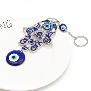 Detailed close-up of Hamsa hand keychain with blue Evil Eye beads on a white plate