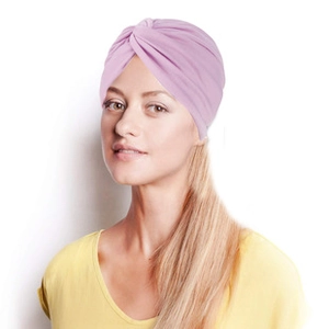 Gros plan sur un turban rose violacé au design torsadé porté par un mannequin sur fond blanc