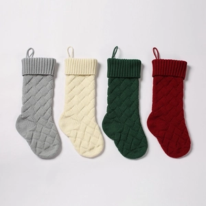 Detail of four knitted Christmas stockings in grey, beige, green, and burgundy with loop hooks