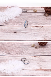 Polished titanium steel rings in blue and black with center crystal on wood surface