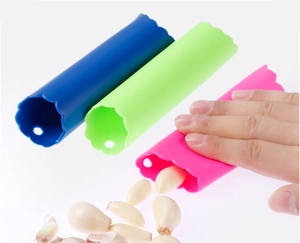 Éplucheurs d'ail en silicone bleu, vert et rose en action avec des gousses fraîches