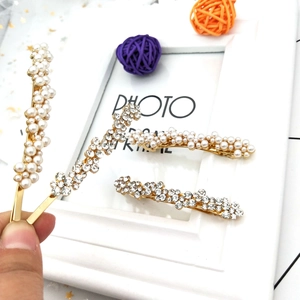 Détail de barrettes à cheveux en perles et strass sur base en métal doré à la main