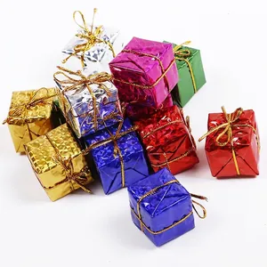 Colorful laser mini Christmas gift box ornaments with gold strings on white background
