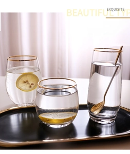 Detail of hammer-textured glass cup with gold rim and elegant golden mixing spoon