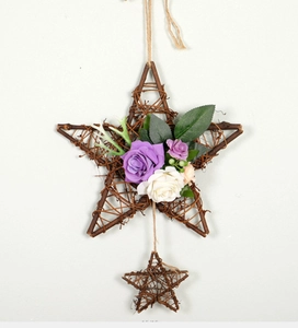 Detail of wooden star hanging with purple and white faux roses and green foliage