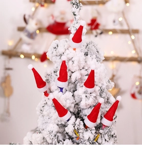 Mini red and white non-woven Christmas hats displayed on a snowy tree branch