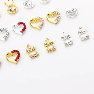 Detailed view of alloy heart and crown nail charms with red rhinestones and pearls