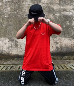 Streetwear style photo of male model in red t-shirt and black pants with logo details
