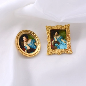 Detailed view of vintage Baroque portrait brooches with ornate gold frames on white fabric