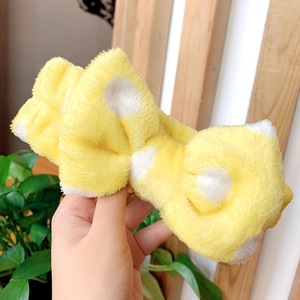 Close-up of soft yellow coral fleece headband with white polka dots for face washing