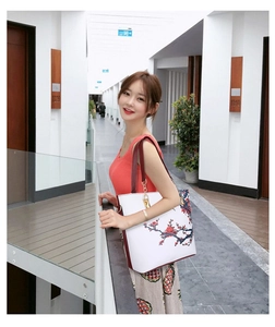 Modern white tote bag with floral print and red strap shown on a model in a minimalist corridor
