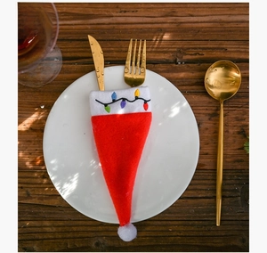 Detailed view of Christmas hat cutlery holder with embroidered colorful lights on a white plate