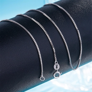 Macro shot of 1mm silver box chain featuring a polished S925 clasp on a black leather stand