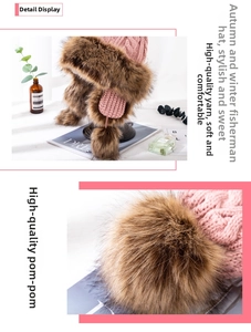 Close-up of pink knitted winter hat with thick brown faux fur trim and fluffy pompom detail