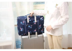 Travel bag with flamingo print secured on a silver suitcase handle via trolley sleeve