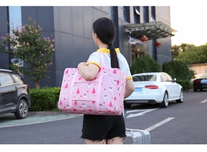 Pink waterproof travel bag with cartoon reindeer print shown carried by a model outdoors