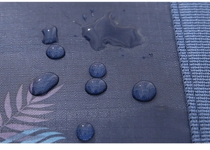 Detailed macro view of waterproof blue fabric with water droplets on a folding travel bag