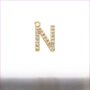 Macro detail of gold-plated brass letter N pendant with micro-pave cubic zirconia