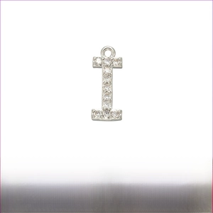 Macro shot of silver letter I pendant with white zircon pavé and brass details