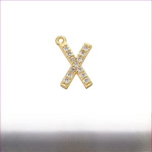 Detailed macro view of gold brass letter X pendant with micro-paved cubic zirconia