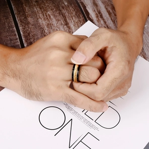Two-tone black and gold titanium steel ring with a brushed finish worn on hand
