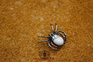 Detail view of spider brooch pendant with white marbled stone inlay and antique silver finish