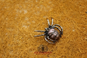 Macro shot of spider brooch pendant featuring a pink natural stone with black veins