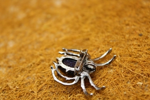 Detailed back view of silver spider brooch with blue goldstone and secure metal clasp pin