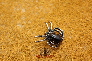 Macro detail of a spider brooch featuring a brown cabochon stone and silver metal legs