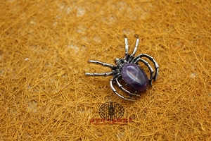 Detailed view of spider brooch with purple crystal stone and antique silver finish