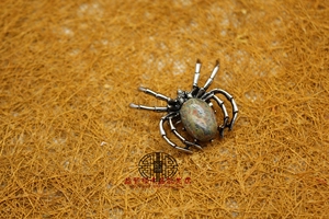 Detail of vintage silver spider brooch with natural green and red jasper stone inlay