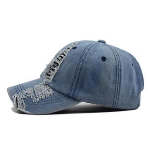 Close-up of distressed denim baseball cap with vintage frayed holes and twill texture