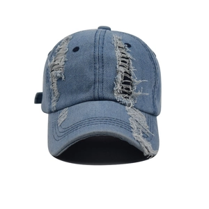 Detailed close-up of distressed denim baseball cap with raw edges and ripped texture