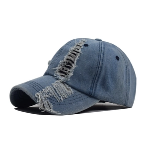 Detail of washed blue denim baseball cap with vintage distressed ripped holes on visor