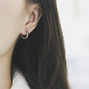 Close-up of minimalist silver huggie earrings worn on model with polished finish