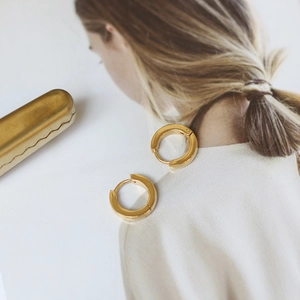 Close-up of minimalist 18K gold plated hoop earrings resting on a stylish magazine