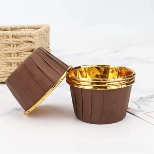 Detail of coffee brown muffin cups with golden foil lining on marble background