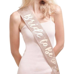 Close-up of rose gold glitter Bride to Be sash with diamond icon and gold safety pin