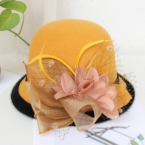 Detail of yellow wool felt fedora featuring pink floral decor and mesh veil with feathers