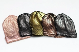 Detail view of five metallic knitted beanies in rose, silver, gold, bronze, and grey colors