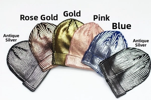 Flat lay of metallic knitted beanies in antique silver, gold, and rose gold finishes