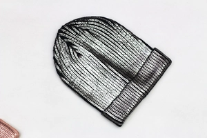 Detailed view of silver metallic knit beanie with reflective laser coating texture