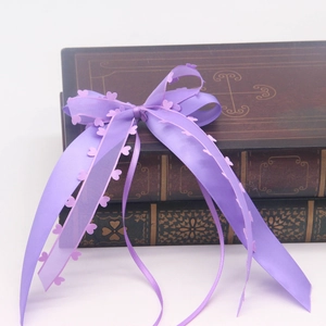 Détail d'un nœud en satin violet avec découpes de cœurs sur des livres vintage