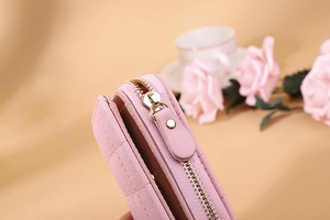 Detailed close-up of pink leather wallet featuring quilted stitching and golden zipper