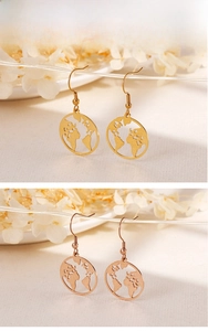 Close-up of gold and rose gold world map hollow pendant earrings for travelers