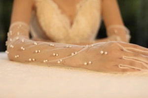 Close-up of bridal white sheer mesh long gloves with pearl embellishments and beadwork