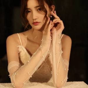 Detail of white bridal tulle gloves with pearls and fingerless lace design for weddings